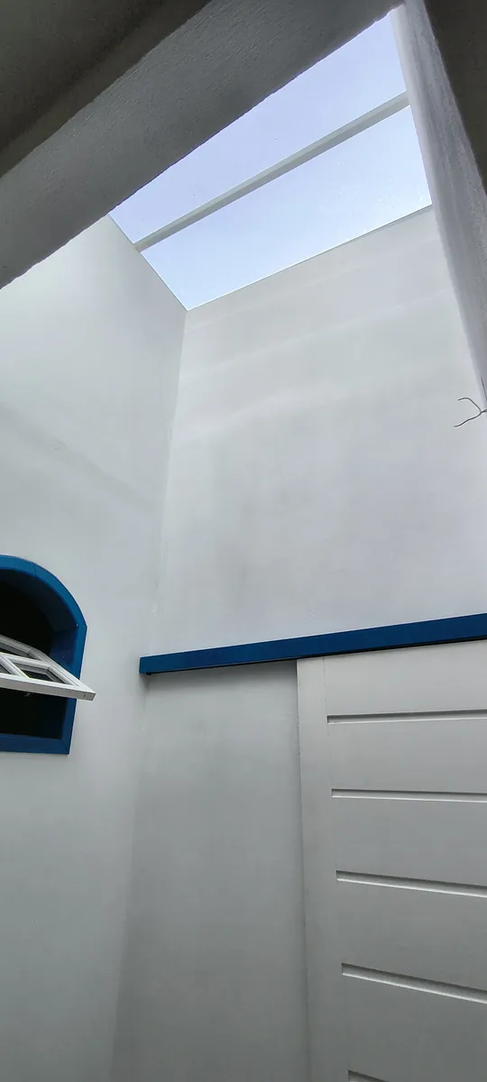 Área interna com claraboia para iluminação natural e detalhes em azul colonial no Sítio Canto da Seriema