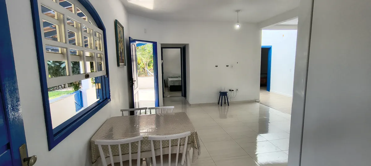 Sala de jantar com janelas e portas coloniais azuis abrindo para o jardim no Sítio Canto da Seriema