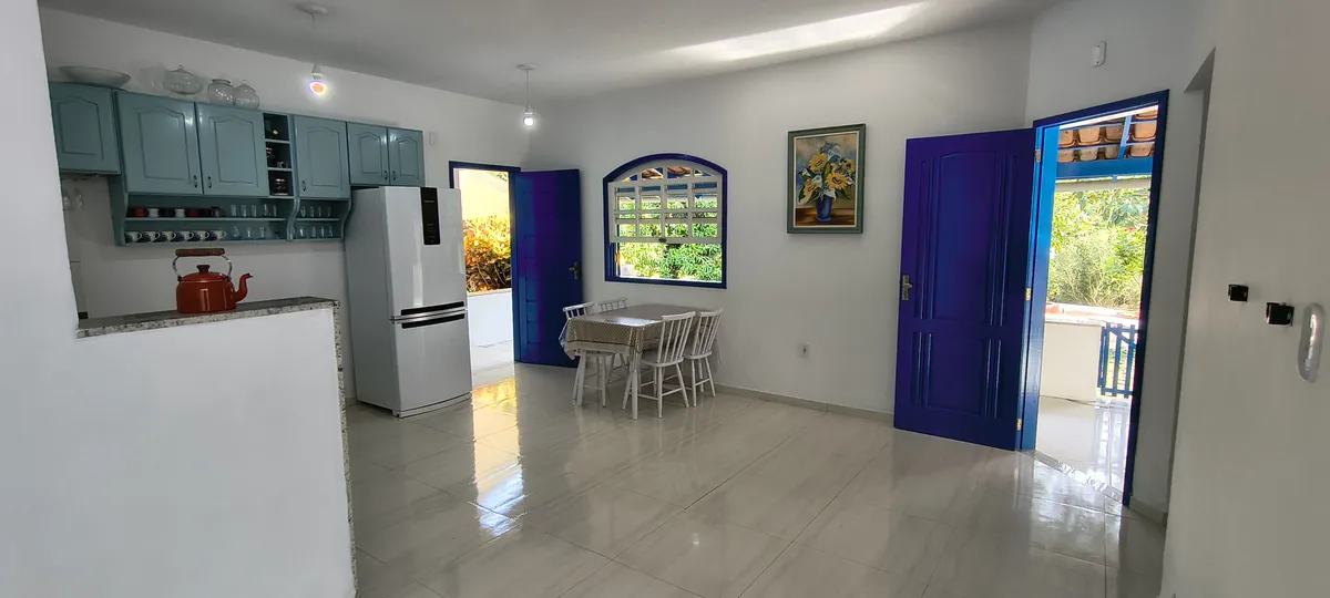 Copa e cozinha com portas abertas para a varanda e vista da vegetação no Sítio Canto da Seriema