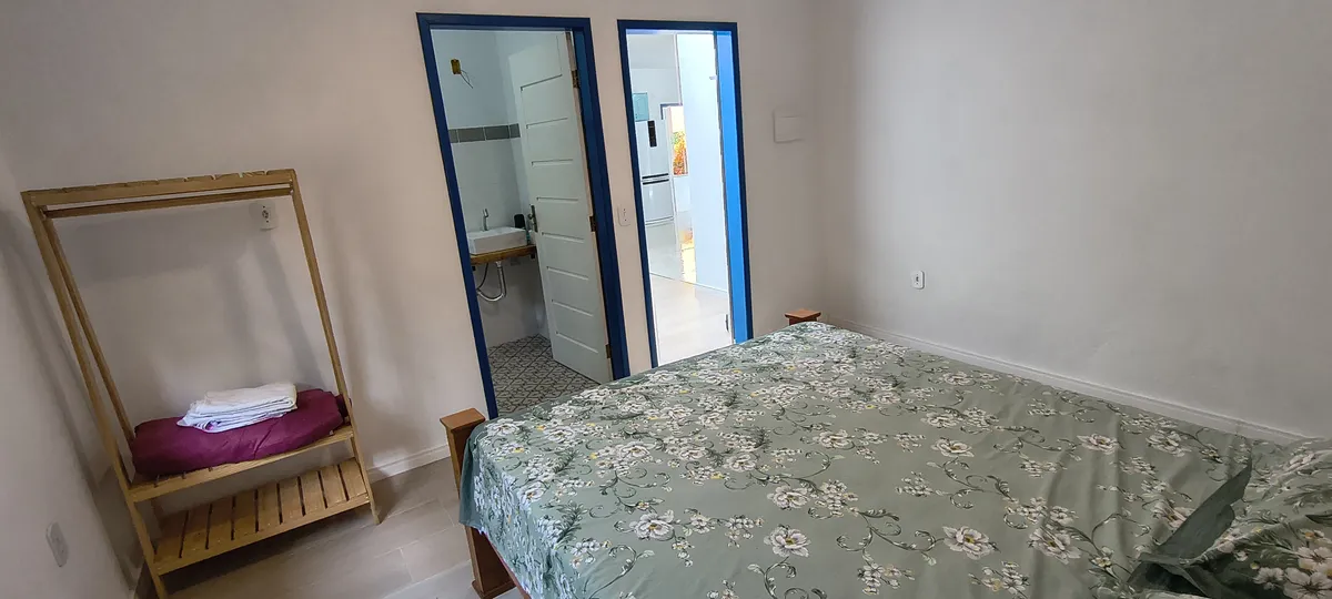 Quarto com cama de casal, arara para toalhas e acesso direto ao banheiro no Sítio Canto da Seriema