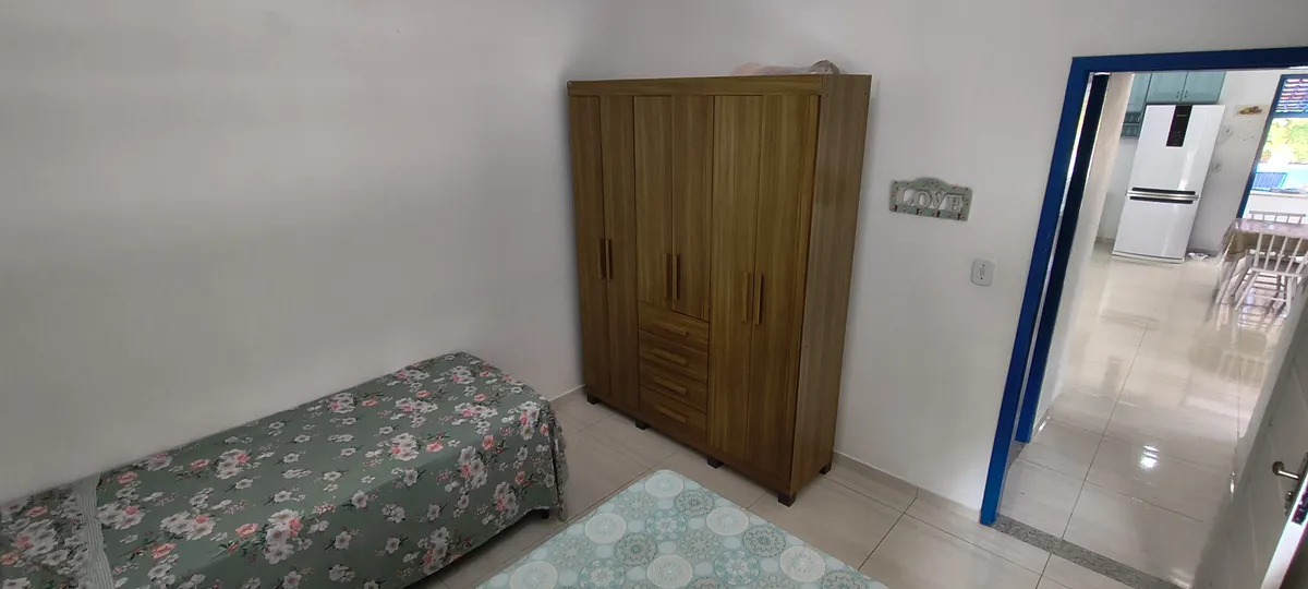 Quarto com camas de solteiro, guarda-roupa em madeira e vista para a cozinha no Sítio Canto da Seriema
