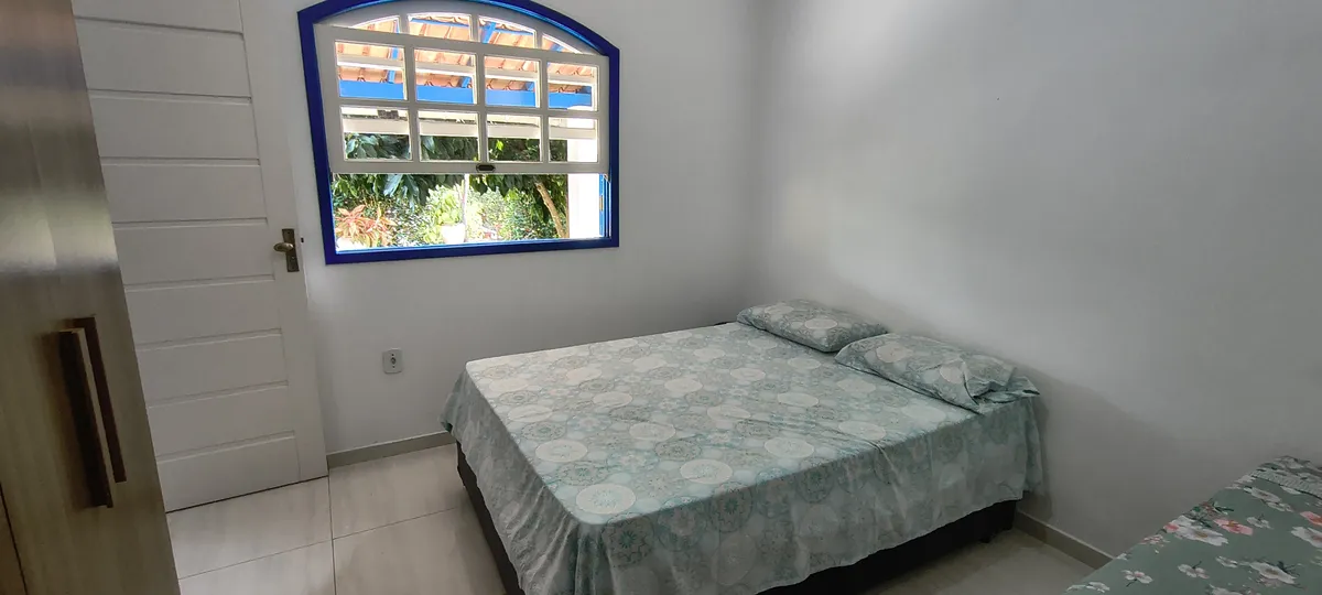 Quarto arejado com cama de casal, janela colonial grande e vista para o pomar no Sítio Canto da Seriema